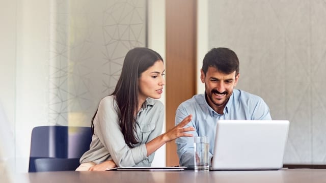 Biopharma professionals reviewing CDMO information together on a laptop during partner evaluation.