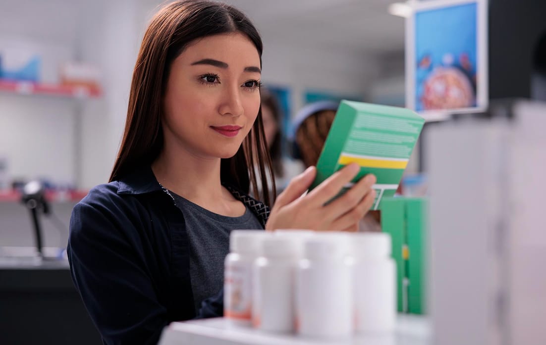 woman holding drugs package looking at pharmaceutical leaflet during medicine shopping in pharmacy, client buying supplements, vitamin for a healthy immune system. Medicine support