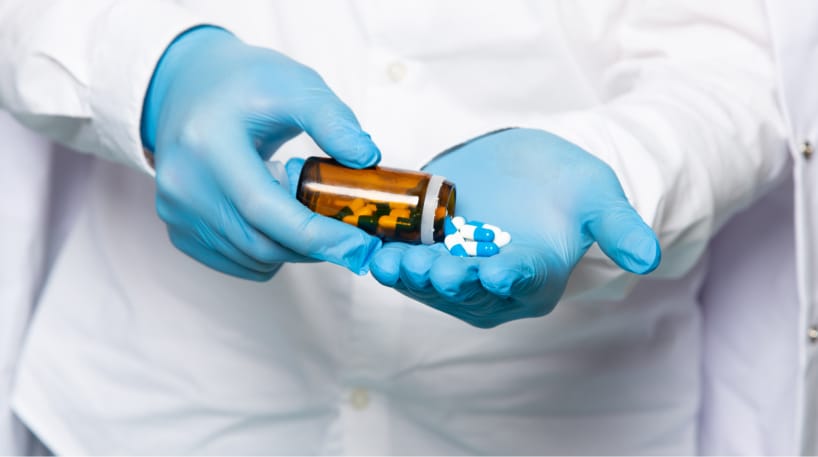 A front view man using pills in white shirt in blue gloves