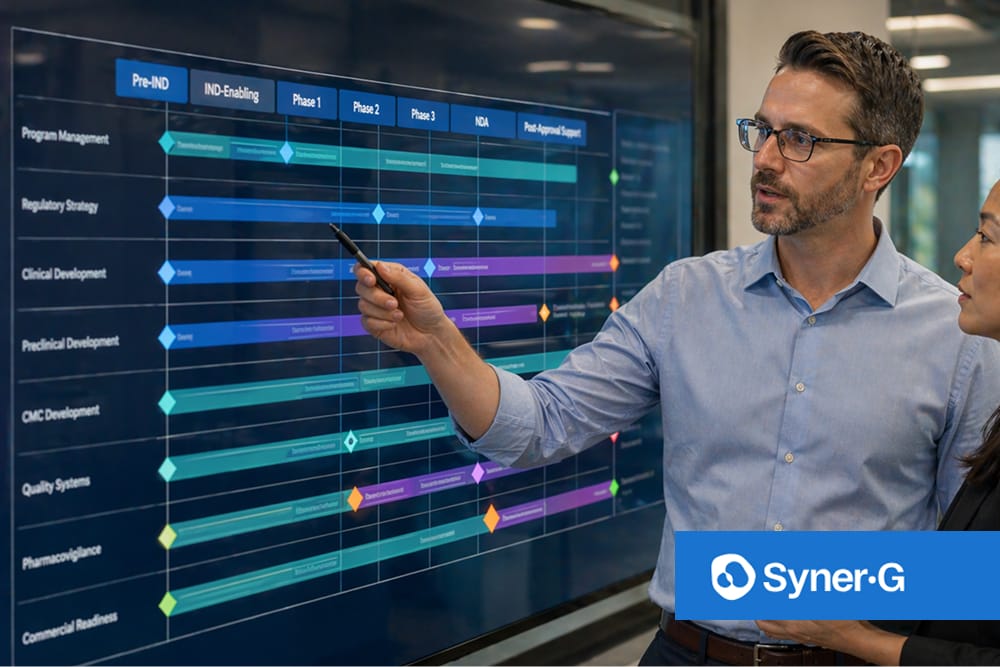 Two biopharma professionals reviewing a regulatory development timeline on a large digital project roadmap display