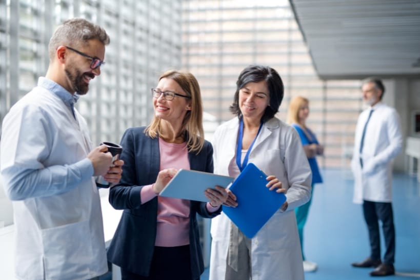 Pharmaceutical and regulatory professionals reviewing documents in a bright medical facility during a clinical strategy and compliance advisory meeting
