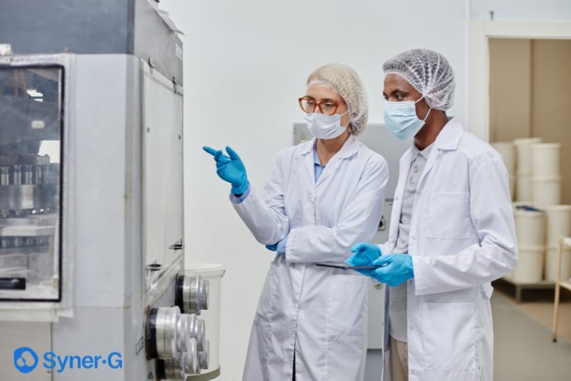 Biopharma professionals reviewing manufacturing equipment during a CDMO technology transfer process.